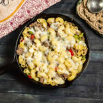 Skillet meal with pasta, thinly sliced steak, onions, peppers, and melted cheese.