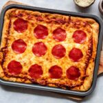 Homemade pizza baked on a sheet pan with assorted toppings.