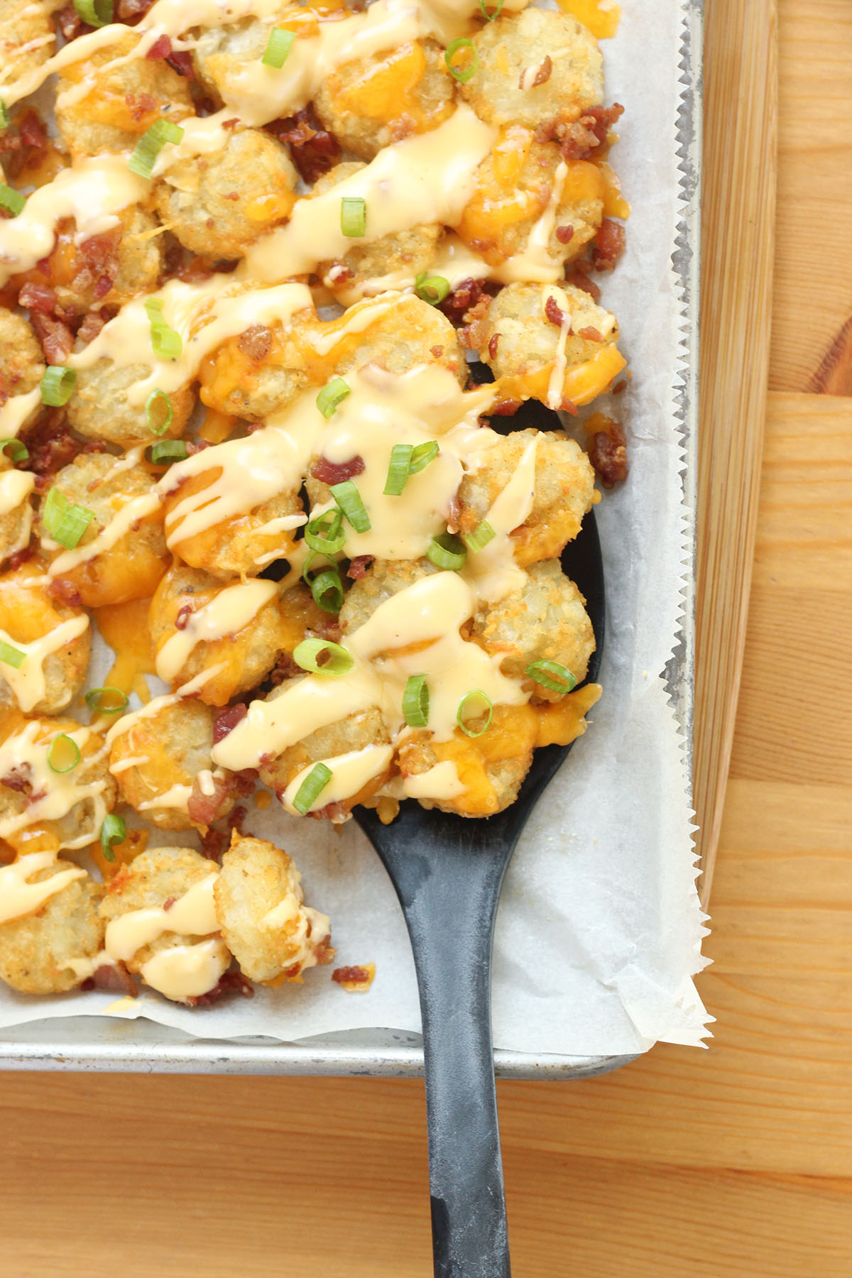 step by step process of layering tater tots with cheese and toppings on baking sheet