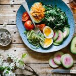 overhead shot of golden bubbly roasted broccoli and cauliflower pasta bake in ceramic baking dish with melted cheese on top