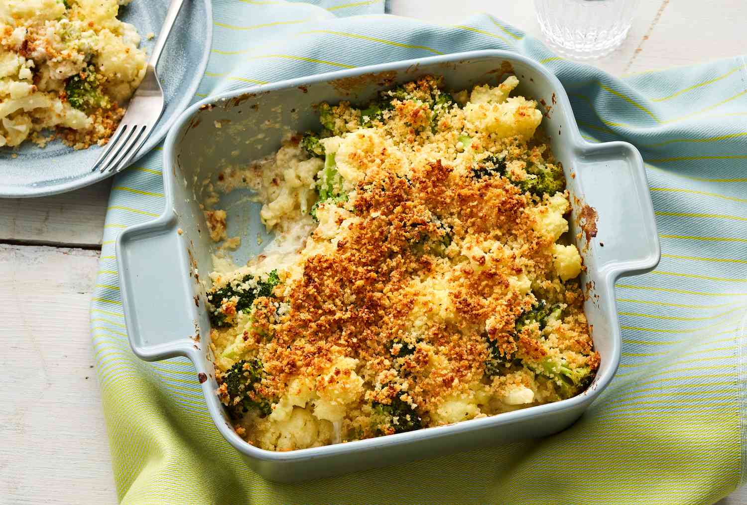 overhead shot of golden bubbly roasted broccoli and cauliflower pasta bake in ceramic baking dish with melted cheese on top