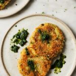 Golden crispy air fryer tikkis arranged on a white plate with vibrant green curry sauce and fresh cilantro garnish