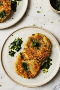 Golden crispy air fryer tikkis arranged on a white plate with vibrant green curry sauce and fresh cilantro garnish