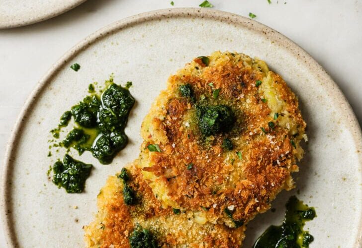 Golden crispy air fryer tikkis arranged on a white plate with vibrant green curry sauce and fresh cilantro garnish