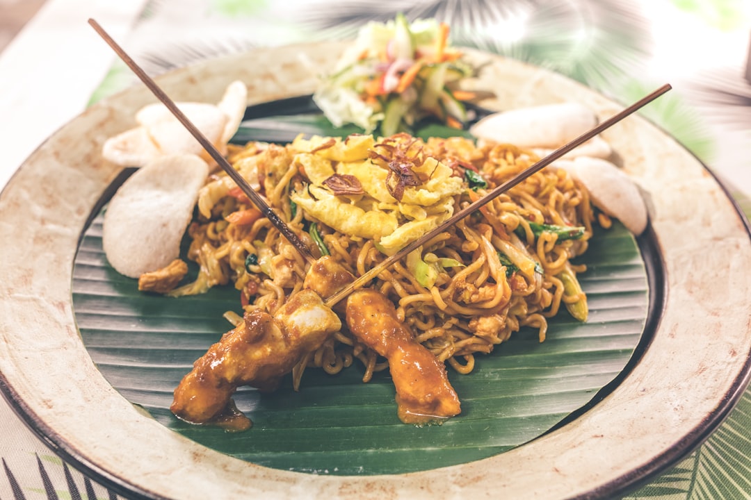 Close up of pad thai noodles wrapped around chopsticks with garnish