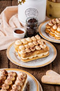 Classic tiramisu in individual glass portions with perfectly dusted cocoa powder on top, garnished with coffee beans