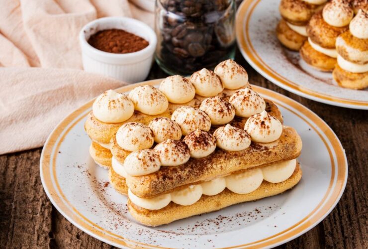 Classic tiramisu in individual glass portions with perfectly dusted cocoa powder on top, garnished with coffee beans