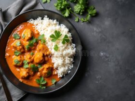 Creamy butter chicken served in a black bowl with basmati rice and fresh cilantro garnish