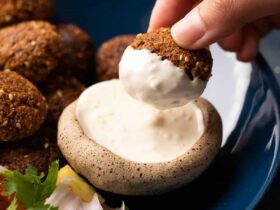 Crispy Falafel Recipe - Perfectly Golden, Healthy Mediterranean Comfort Food 34 Golden crispy falafel balls arranged on a white plate with tahini drizzle, fresh parsley, and colorful vegetables