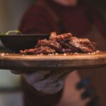 Perfectly shredded healthy crockpot pulled pork served on a rustic wooden platter with fresh herbs and colorful vegetables
