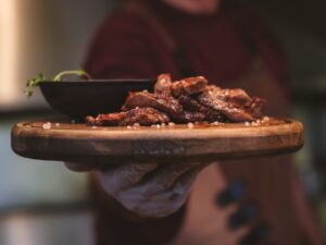Perfectly shredded healthy crockpot pulled pork served on a rustic wooden platter with fresh herbs and colorful vegetables
