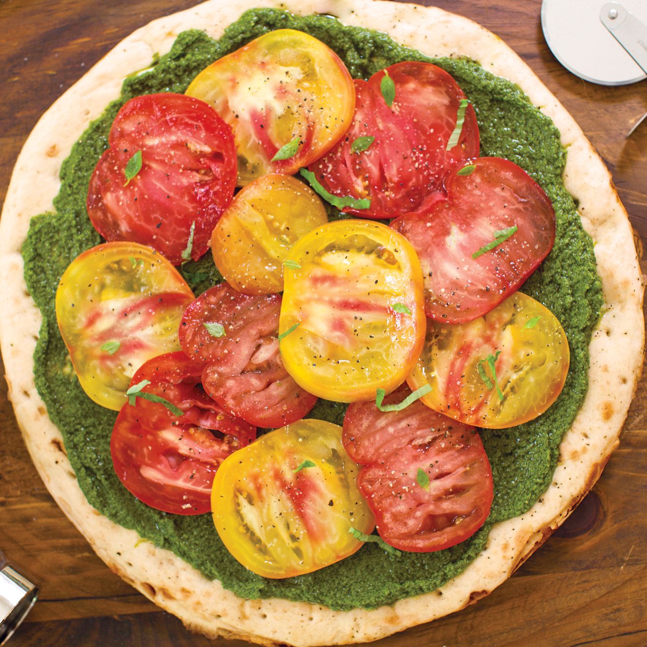 Heirloom Tomato and Pesto Pizza - Fresh Summer Flavors on Homemade Crust 25 Overhead shot of heirloom tomato and pesto pizza with colorful tomato varieties arranged on golden crust with fresh basil garnish