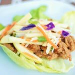 Hoisin turkey lettuce wraps arranged on white platter with garnishes