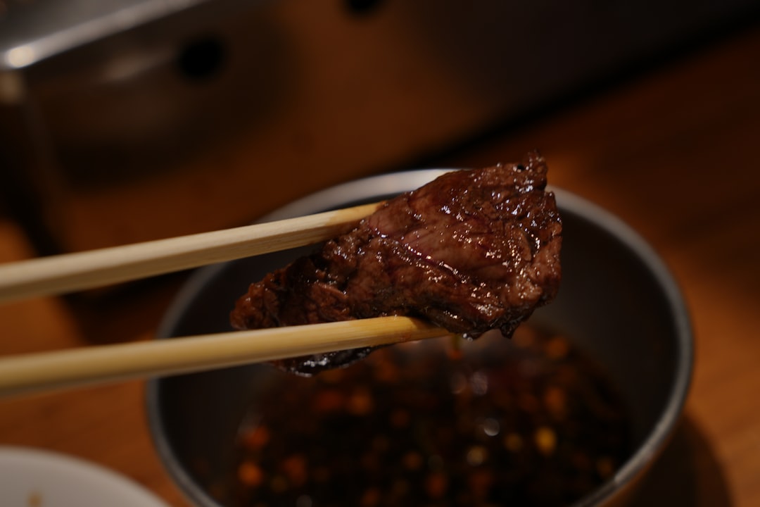 Close-up shot of a spoonful of Japanese beef curry being lifted from the bowl, showing the rich, glossy sauce coating tender beef and vegetables