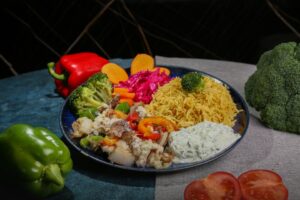 Mediterranean chicken bowl with golden herb-crusted chicken, colorful vegetables, quinoa and tzatziki beautifully arranged in a white ceramic bowl