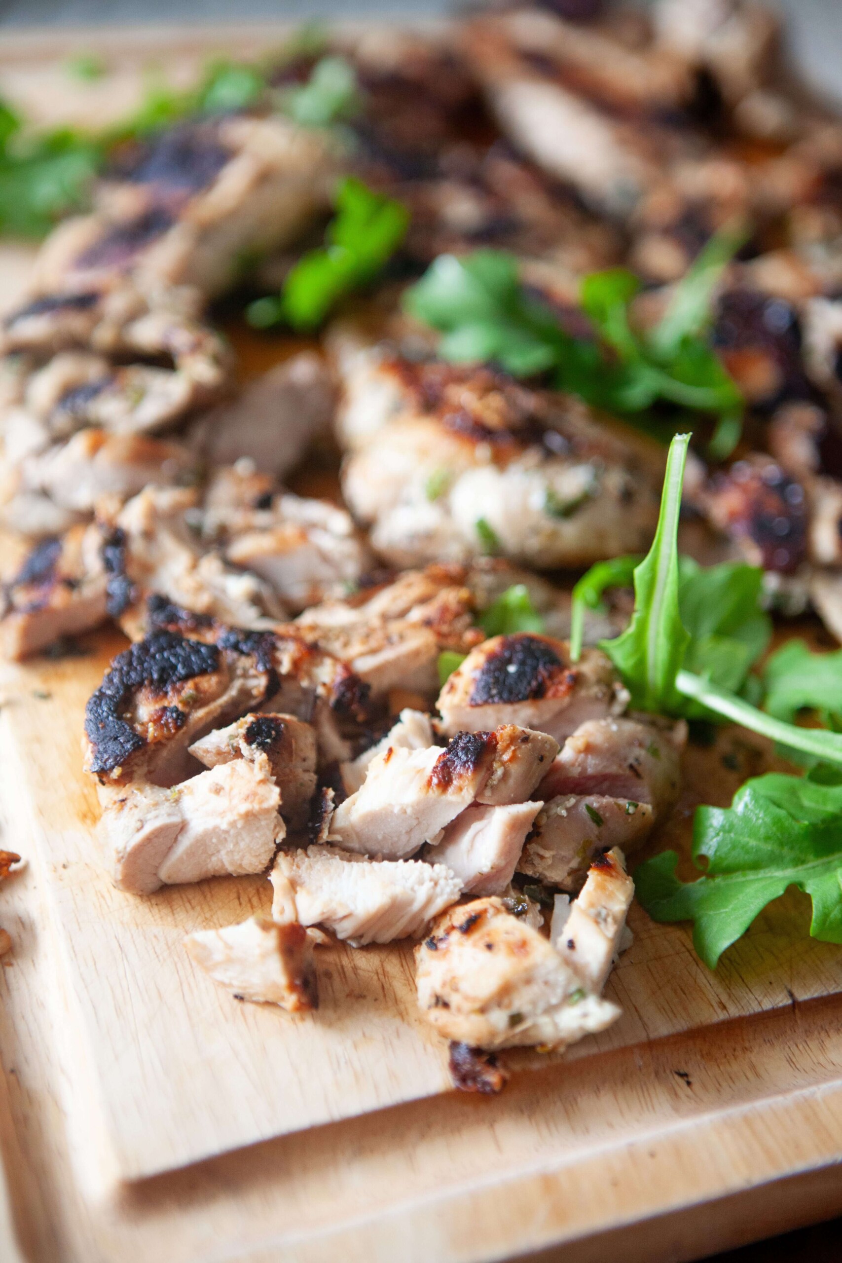 Mediterranean Chicken Bowl - Fresh, Healthy & Packed with Flavor 27 Raw marinated chicken thighs with herbs and colorful chopped vegetables arranged on a wooden cutting board