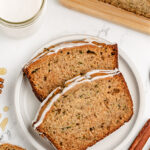 golden brown zucchini bread loaf sliced on wooden cutting board with butter and honey
