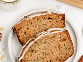 golden brown zucchini bread loaf sliced on wooden cutting board with butter and honey