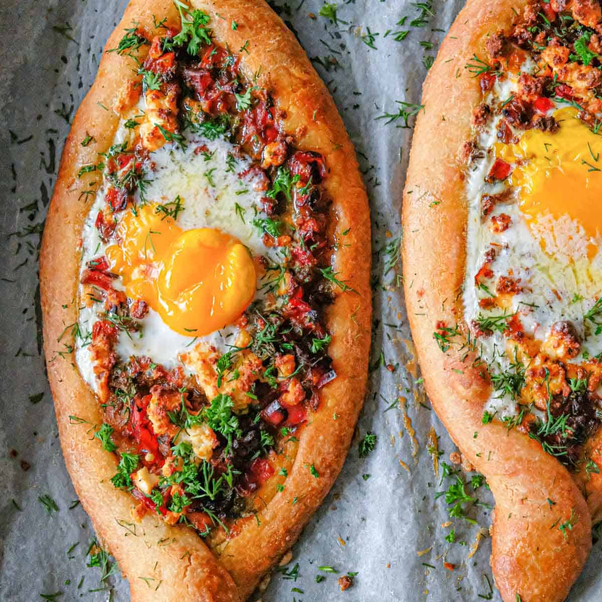 Close-up of shakshuka showing perfectly runny egg yolk being broken with fork, with fresh bread for dipping