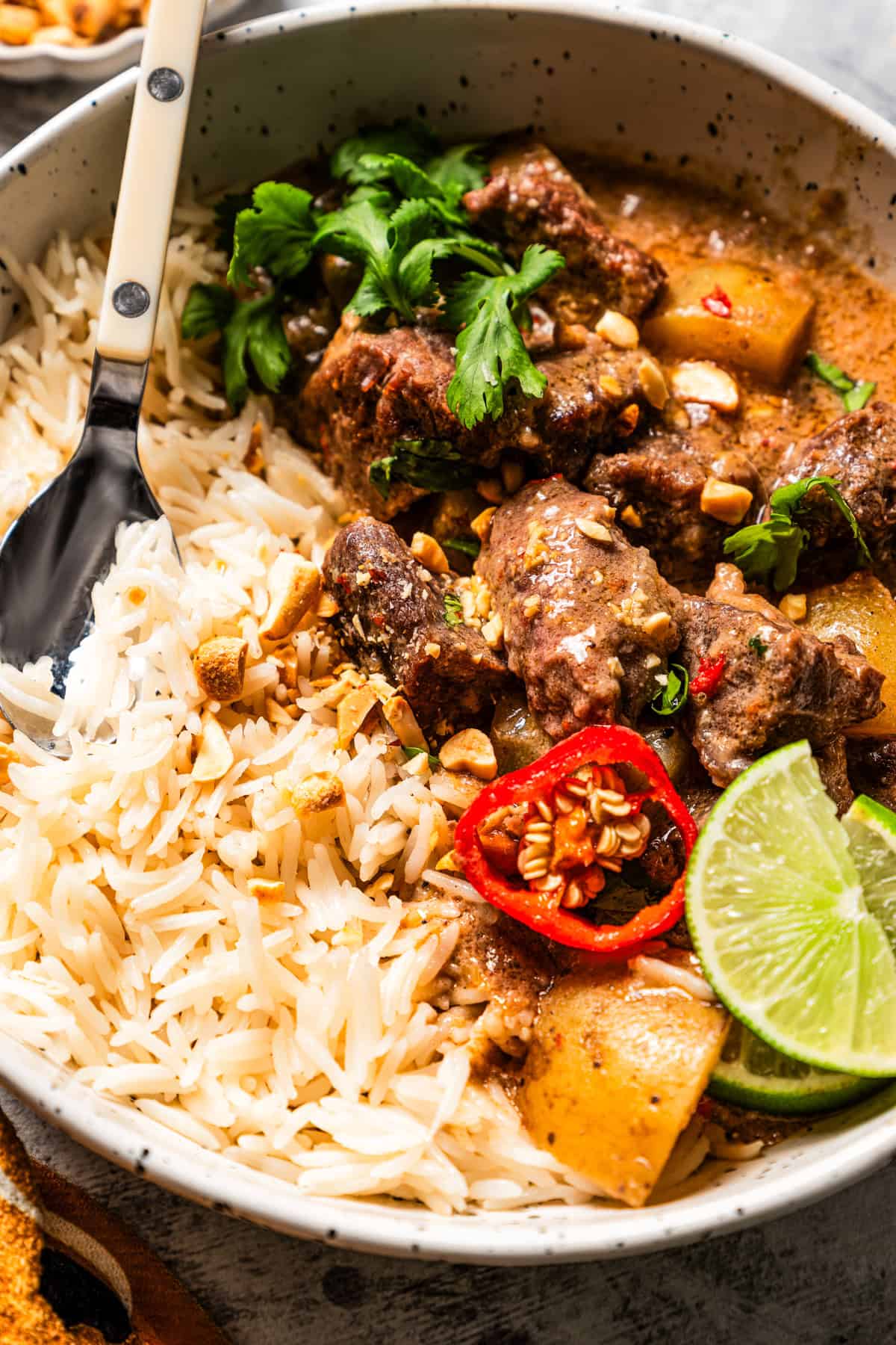 close up of spicy beef massaman curry with steam rising served over jasmine rice