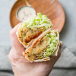 Trader Joe's style spicy lentil wrap cut in half showing colorful filling with lentils and vegetables on rustic wooden board