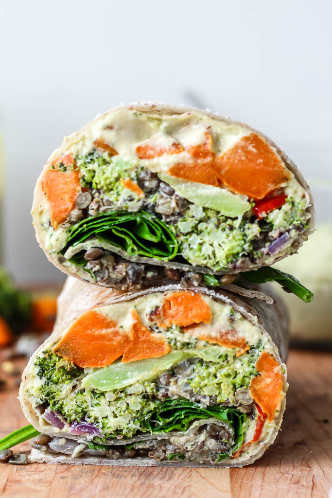 Close up cross section of spicy lentil wrap showing layers of filling and garnished with fresh herbs