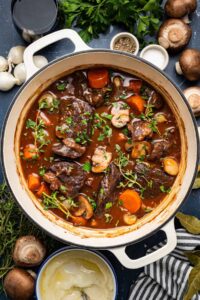Beef Bourguignon Recipe - A Nutritious French Classic Worth the Wait 13 Elegant beef bourguignon in a rustic ceramic bowl with tender beef chunks, pearl onions, and mushrooms in rich wine sauce, garnished with fresh thyme