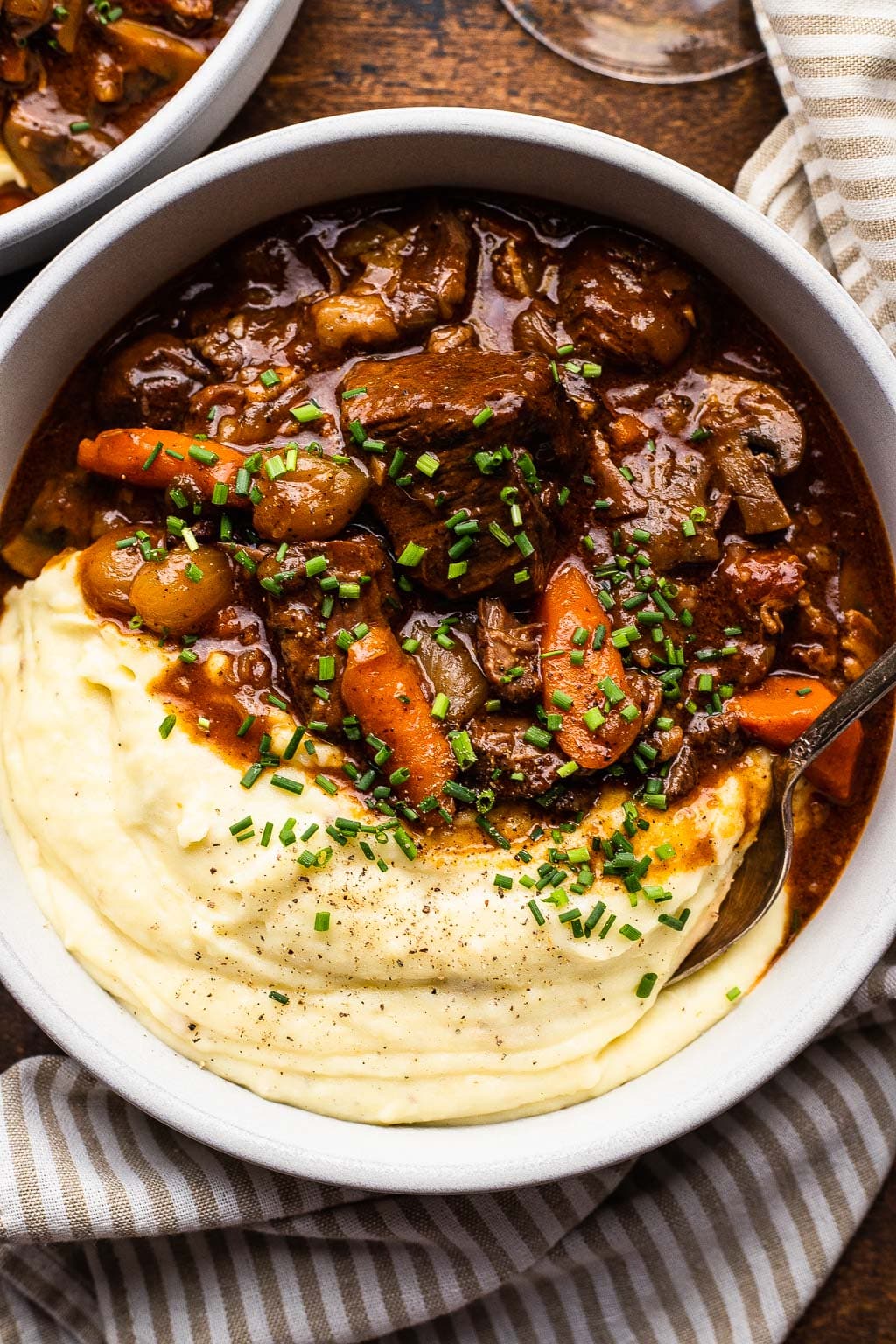 Step-by-step shot showing beautifully browned beef chunks in a dutch oven with caramelized onions and herbs