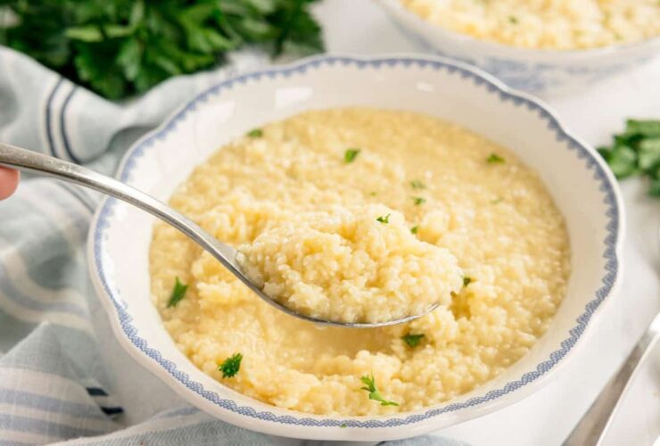 Creamy buttered pastina in a white ceramic bowl garnished with fresh parsley and grated Parmesan cheese