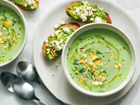 Cold Cucumber Avocado Soup No Cook Recipe - Fresh Summer Nutrition in 10 Minutes 12 Elegant bowl of pale green cold cucumber avocado soup garnished with fresh herbs, cucumber slices, and a drizzle of olive oil, served on a light wooden board with crusty bread