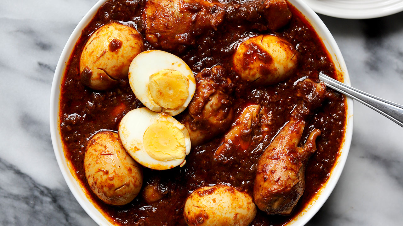 Ethiopian Doro Wat served in a traditional clay pot with hard-boiled eggs, garnished with fresh herbs, alongside injera bread