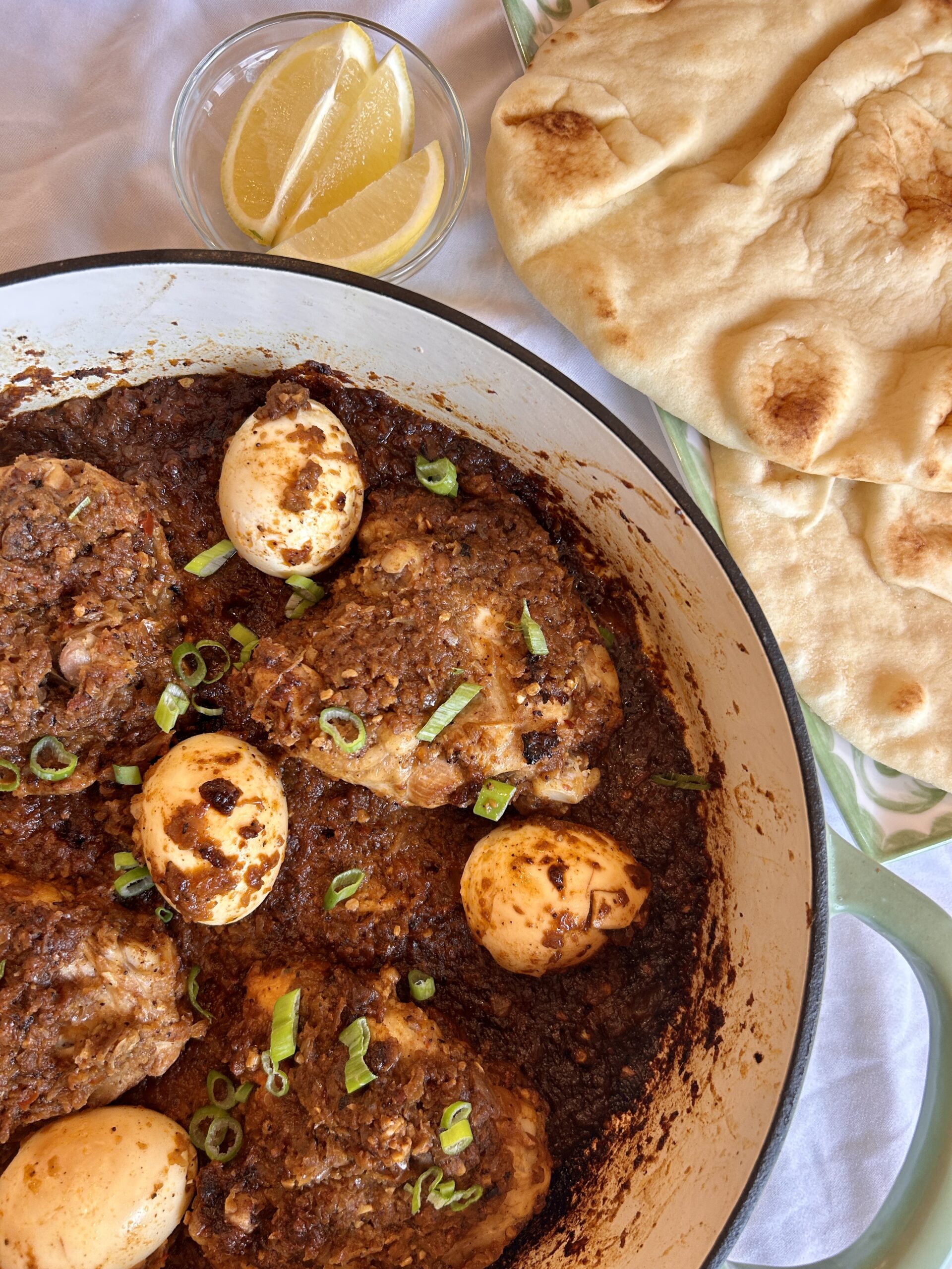 Close-up shot of Ethiopian Doro Wat showing tender chicken and hard-boiled egg in rich, spiced sauce with fresh herb garnish