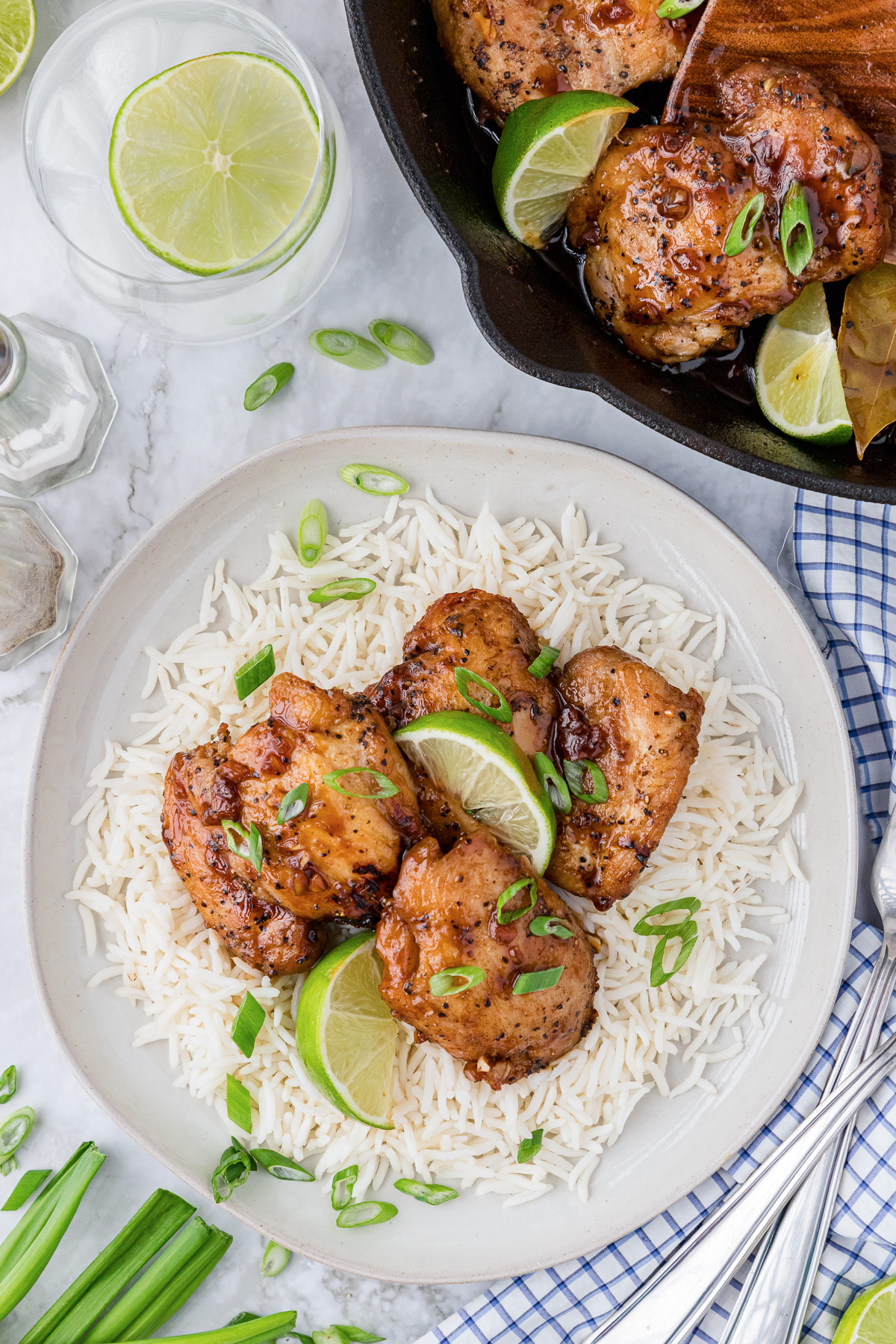 Close-up shot of tender chicken adobo with glossy, caramelized sauce, served over steamed jasmine rice with a lime wedge garnish