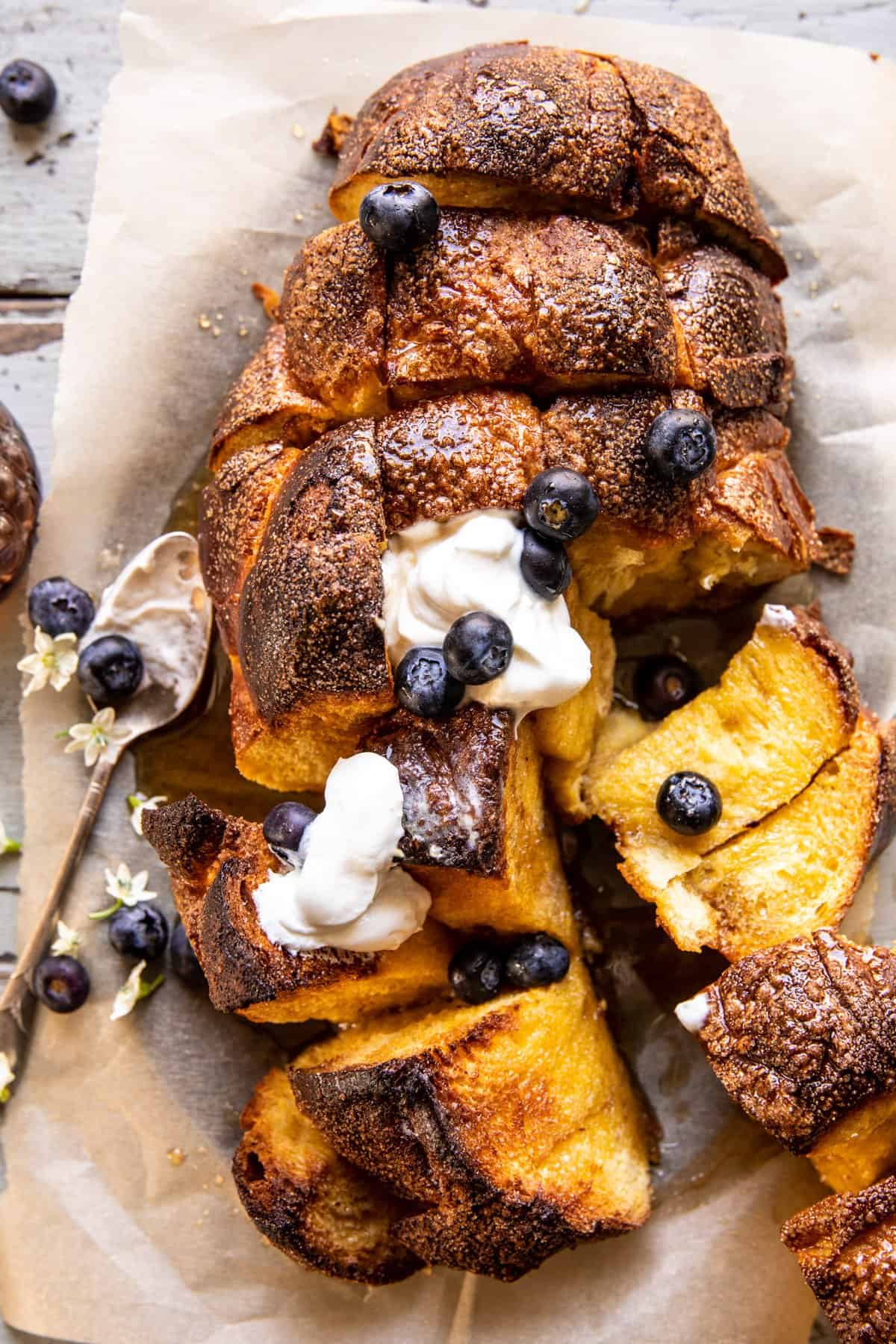 French Toast Casserole - Make-Ahead Breakfast with Clean Ingredients & Nutritional Benefits 27 Hands cutting day-old whole grain bread into cubes on wooden cutting board with custard mixture in glass bowl nearby