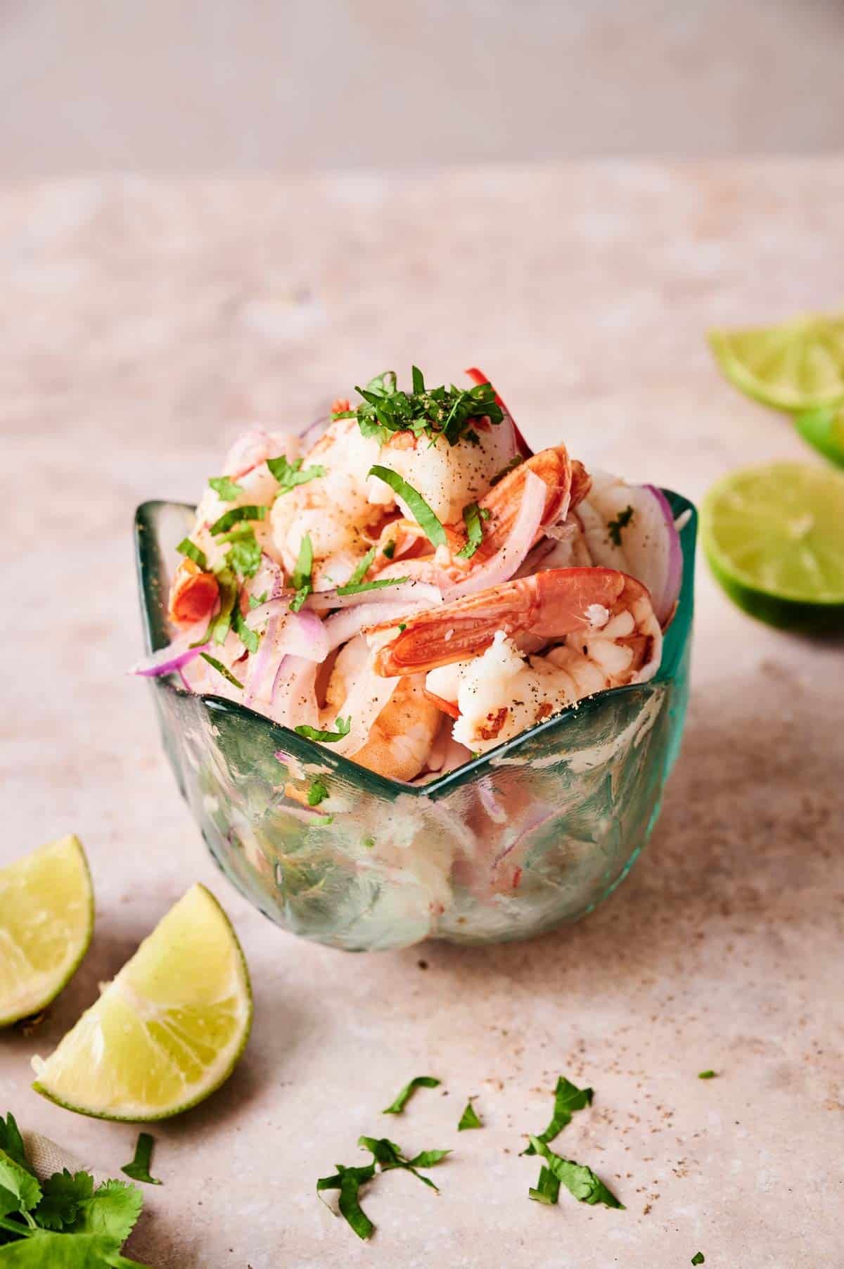 Close-up shot of shrimp ceviche served on individual spoons as appetizers with a sprinkle of black pepper and cilantro garnish