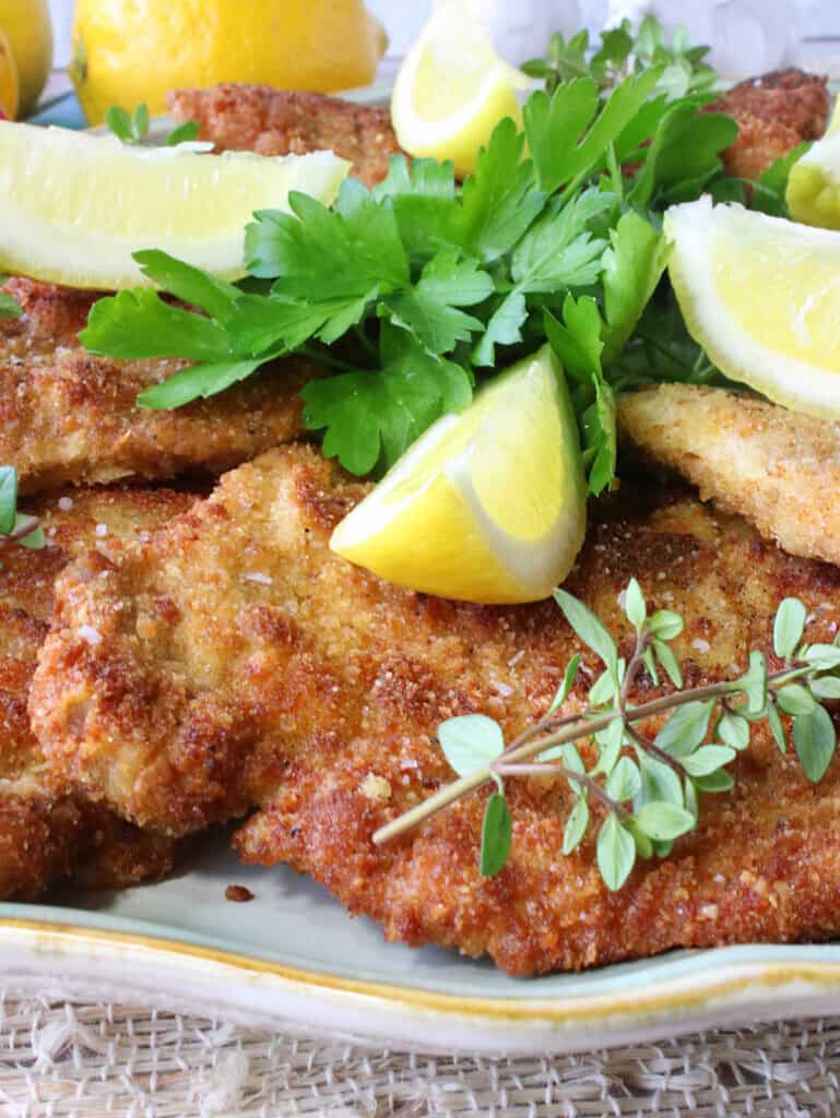 German Schnitzel Recipe - Classic European Comfort Food with Nutritional Benefits 26 Golden German schnitzel cutlets plated elegantly with lemon wedges and fresh herbs on a white ceramic plate