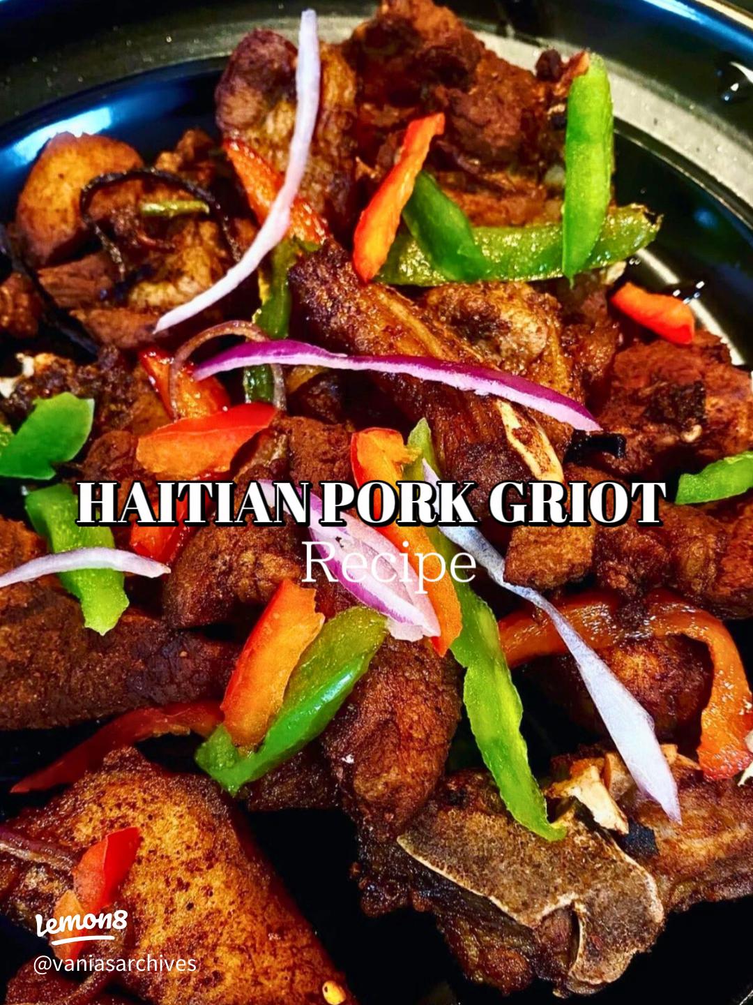 Crispy golden Haitian griot pork pieces garnished with fresh herbs on a white platter with lime wedges