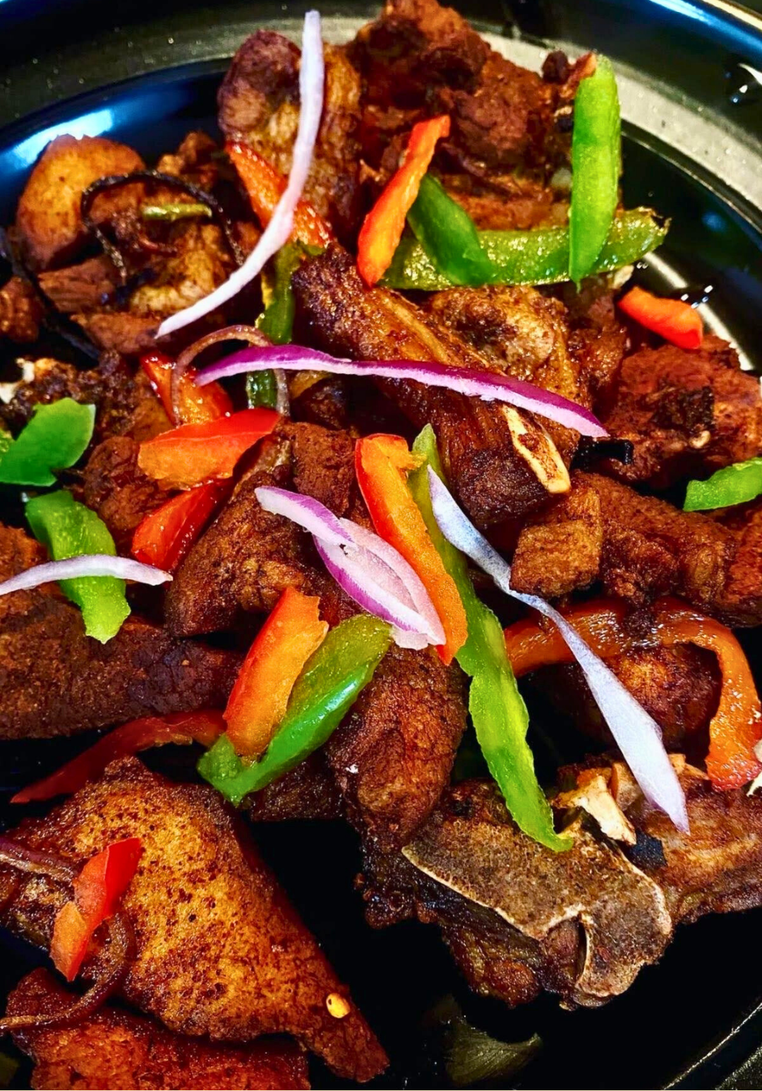 Close-up of crispy griot pieces on a fork with steam rising, showing the golden-brown exterior and tender interior