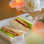 Beautiful banh mi sandwich cut in half showing colorful layers of pickled vegetables, fresh herbs, protein and Vietnamese mayo on crusty French bread
