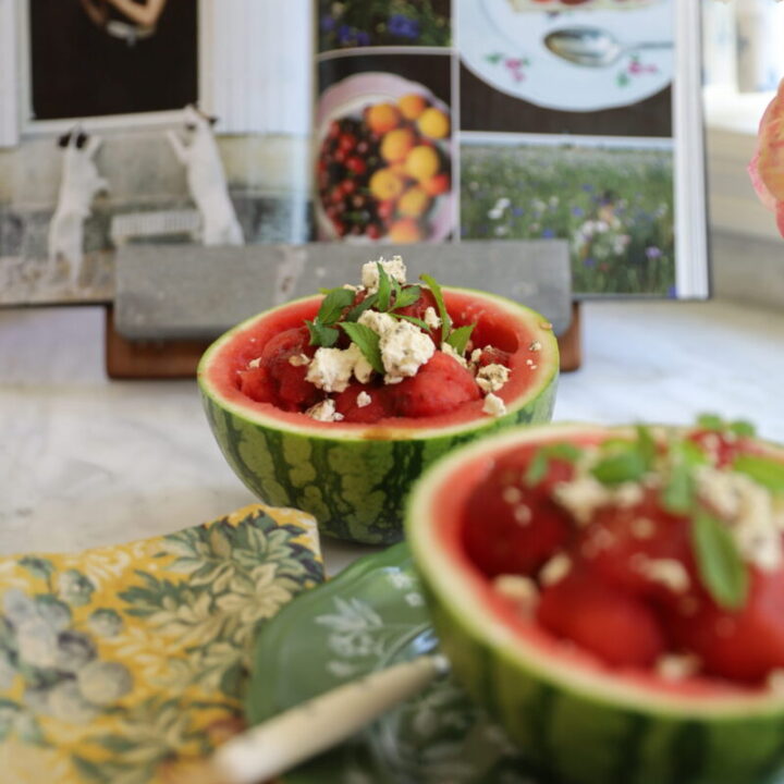 Close-up of watermelon feta mint salad served in individual glass bowls with lime wedges as garnish
