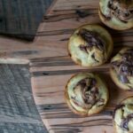 Freshly baked golden cinnamon rolls with cream cheese glaze drizzled on top, arranged on a rustic wooden board with cinnamon sticks and a cup of coffee