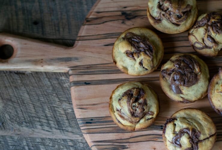 Freshly baked golden cinnamon rolls with cream cheese glaze drizzled on top, arranged on a rustic wooden board with cinnamon sticks and a cup of coffee