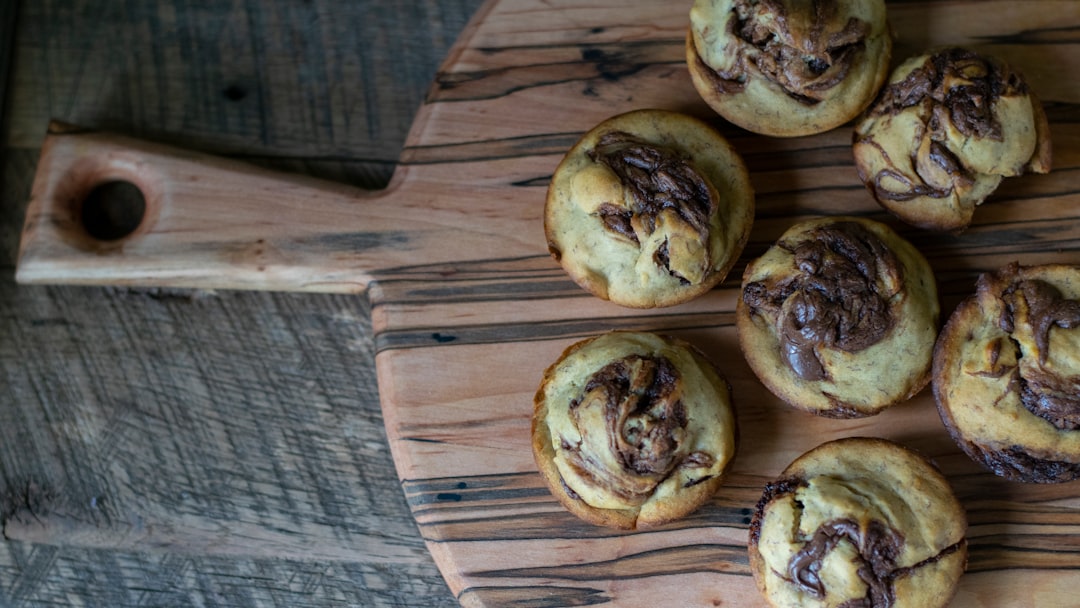 Freshly baked golden cinnamon rolls with cream cheese glaze drizzled on top, arranged on a rustic wooden board with cinnamon sticks and a cup of coffee