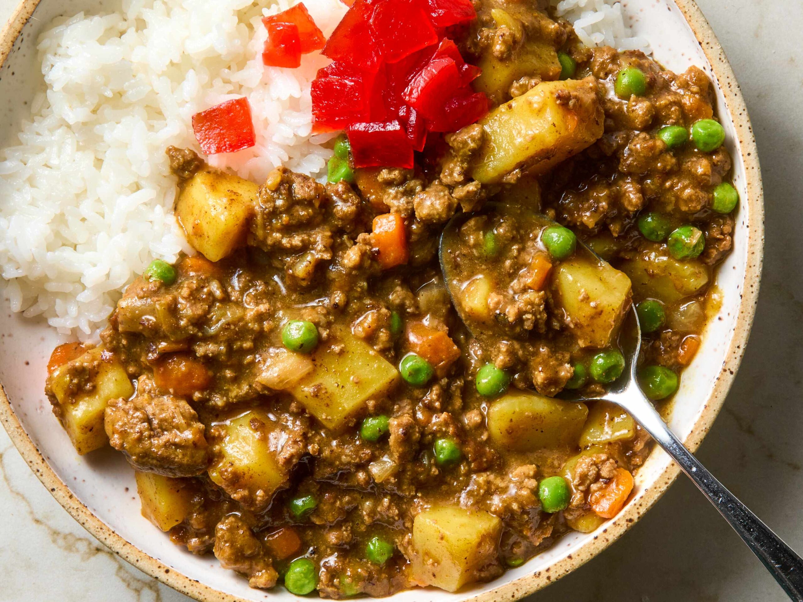 Ingredients for Japanese beef curry laid out on a wooden cutting board, including cubed beef, chopped vegetables, spices, and curry powder in small bowls