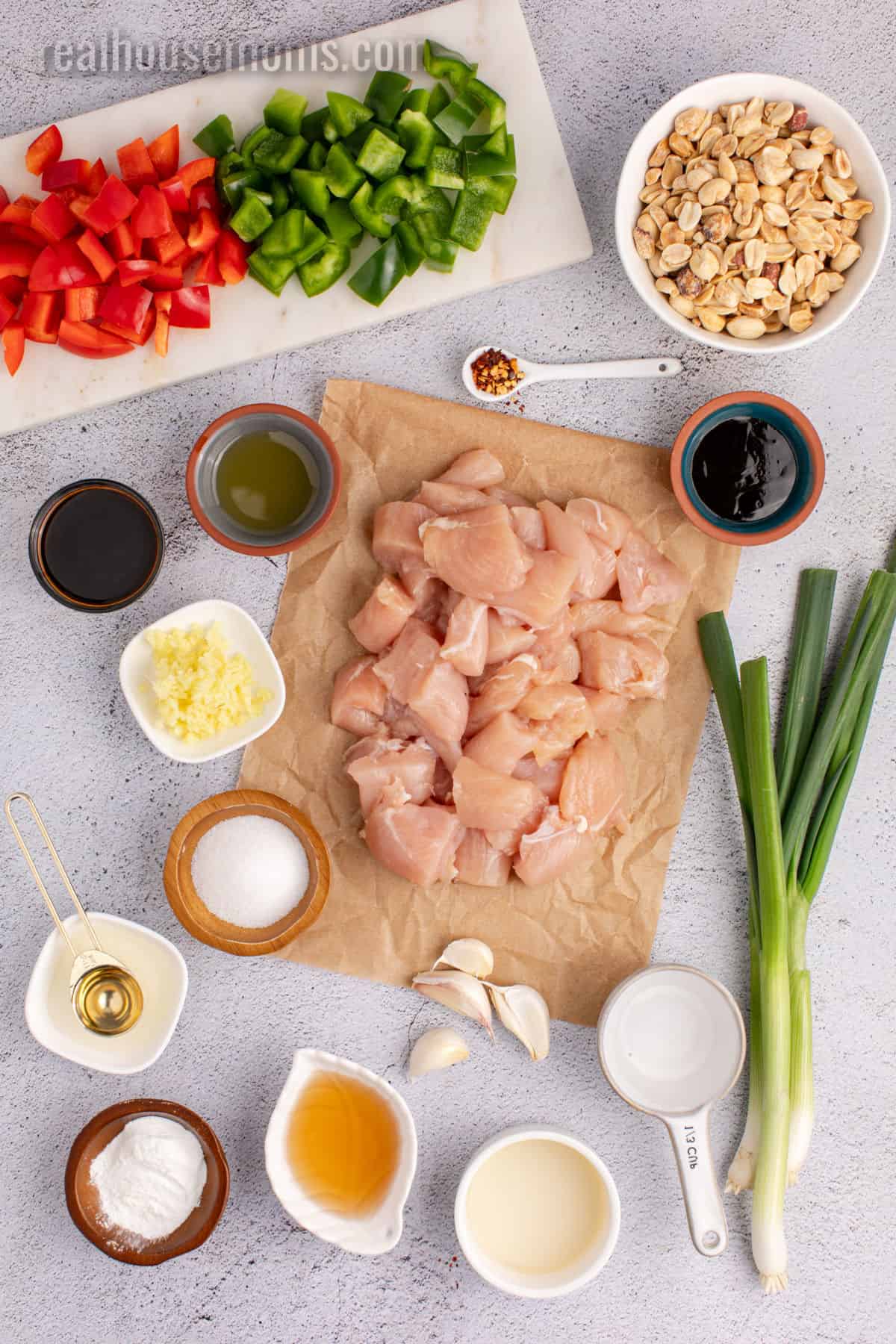 Ingredients laid out on a cutting board showing diced chicken, colorful vegetables, peanuts, and sauce ingredients in small bowls