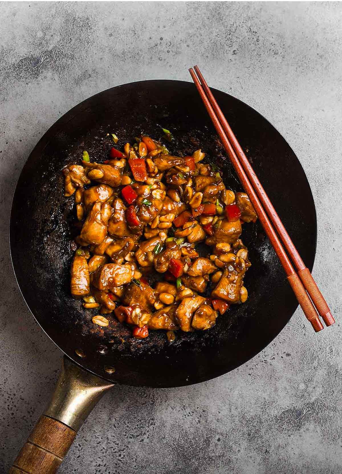 Close-up shot of Kung Pao Chicken on a fork showing the glossy sauce coating and tender chicken with peanuts