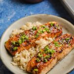 Beautifully plated miso glazed salmon with caramelized golden edges, garnished with sesame seeds and scallions on a white plate