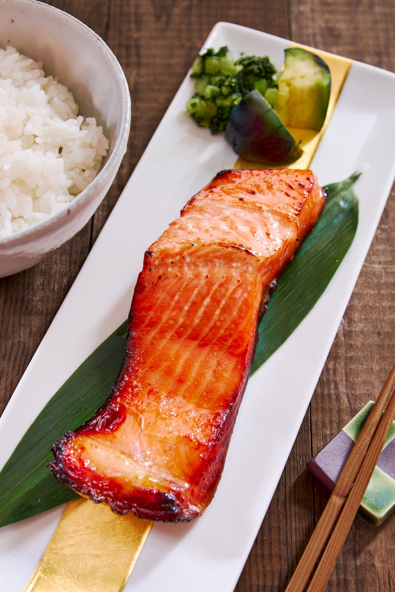 Close-up shot of flaky miso glazed salmon with chopsticks beside it, showing the caramelized glaze and tender interior