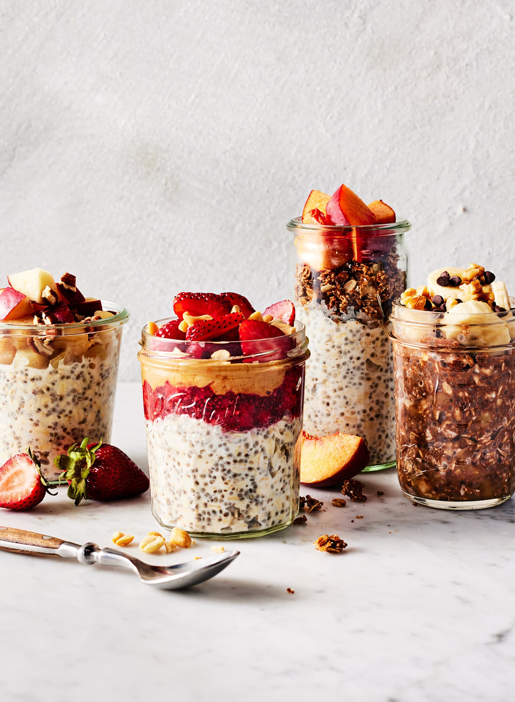 Overnight Oats Summer Berry Recipe — The Ultimate No-Cook Breakfast Jar 27 Flat lay of glass mason jars, rolled oats in a ceramic bowl, fresh mixed berries in small dishes, Greek yogurt in a white bowl, chia seeds, honey, and vanilla extract arranged on a marble surface with natural light
