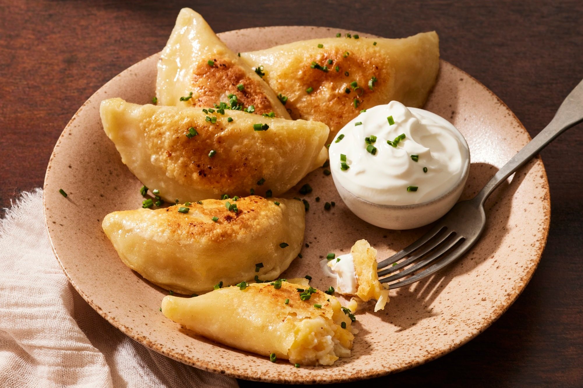 Polish Pierogi Recipe - Authentic European Comfort Food with Nutritious Ingredients 28 Close-up shot of a single pierogi cut in half, showing the creamy potato and cheese filling, with golden-brown edges and a sprinkle of fresh herbs